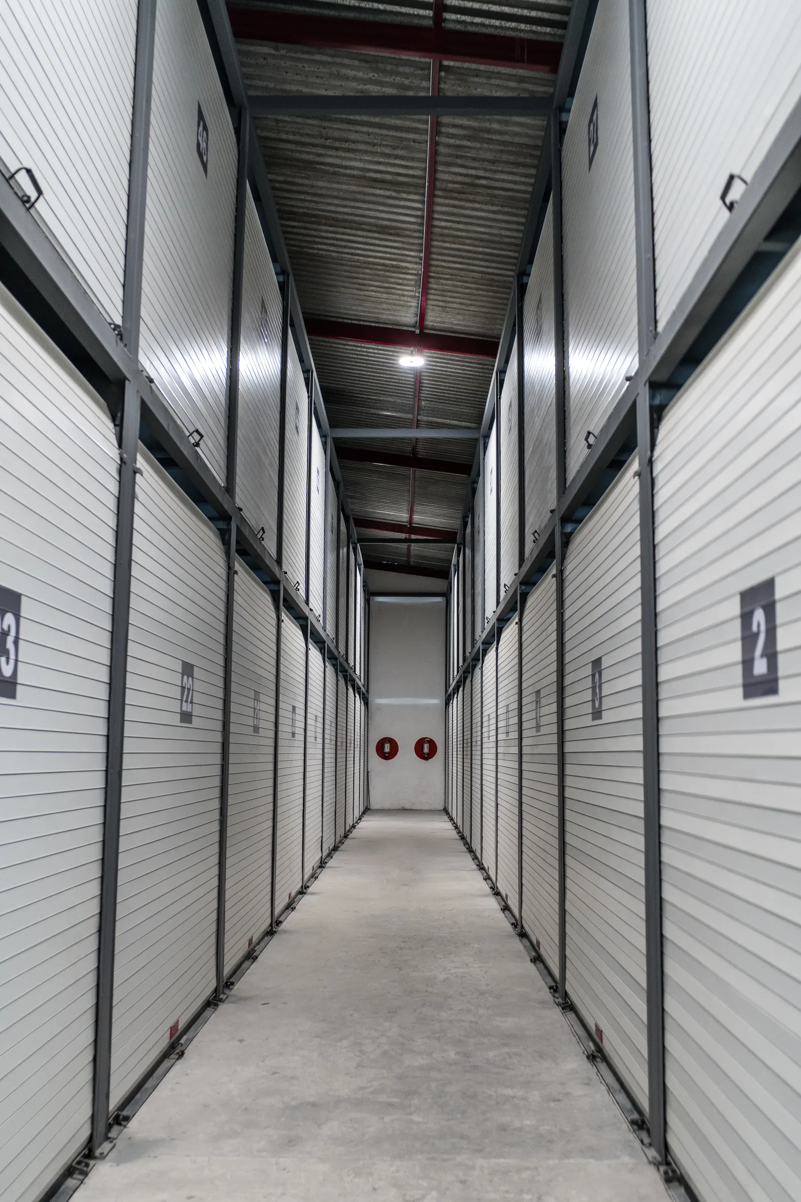 Pasillo de mini bodegas con cortinas metálicas numeradas